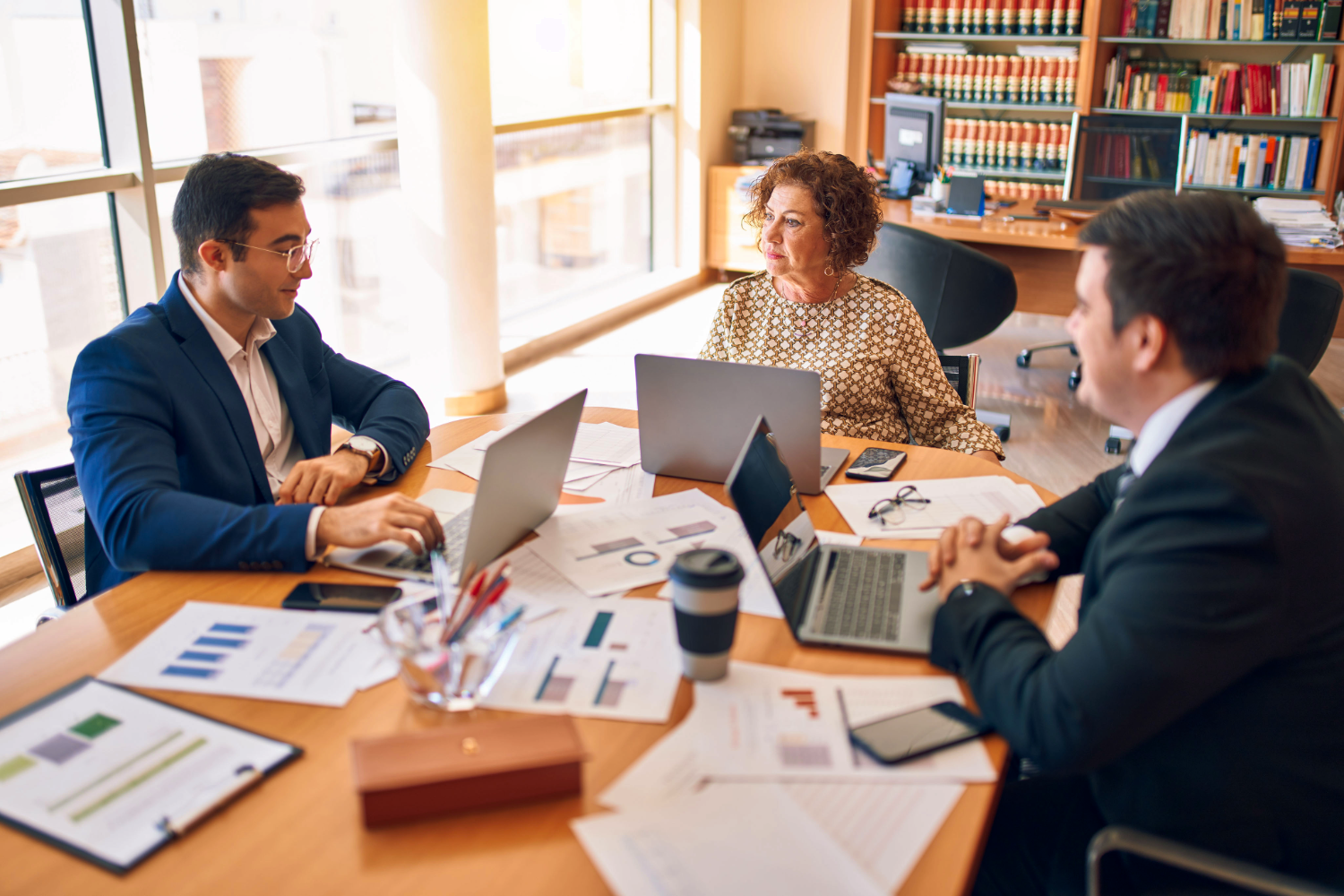 Three professionals in business meeting with laptops and documents